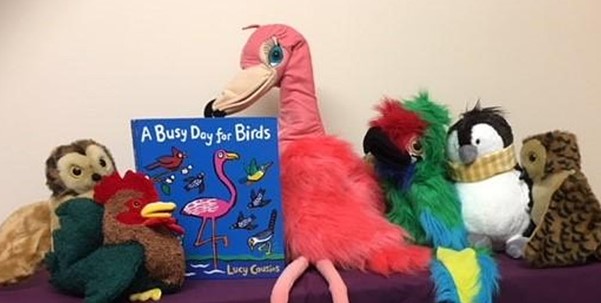 Several cuddly toy animals with the book 'A Busy Day for Birds' by Lucy Cousins