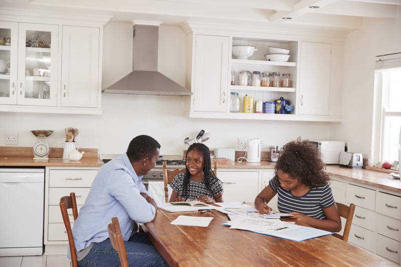 Family sitting at a table writing and talking