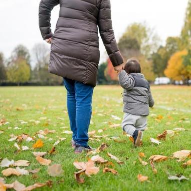 Woman and boy holding hands walking in a park