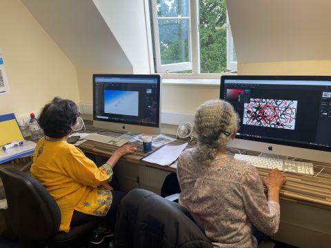 Two members of Community Focus using computers to create digital art.