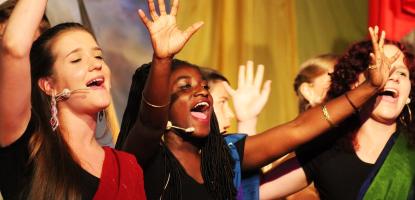 Photo of people in performance with raised hands